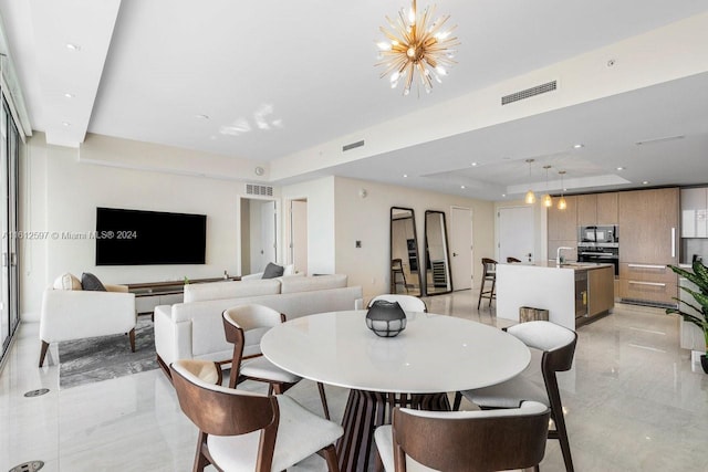 dining space featuring a raised ceiling, sink, and a chandelier