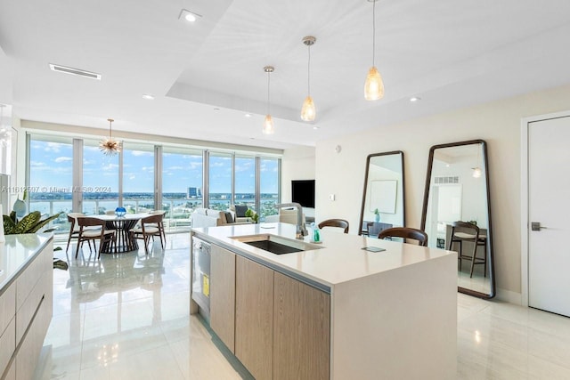 kitchen with plenty of natural light, sink, decorative light fixtures, and an island with sink