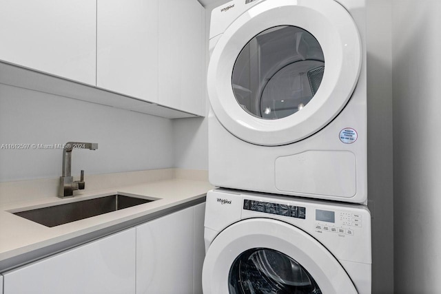 laundry room featuring cabinets, sink, and stacked washer and clothes dryer