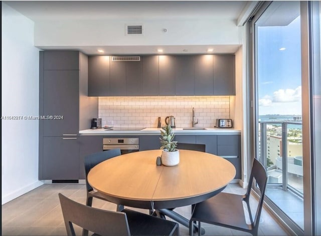 kitchen with sink, gray cabinetry, decorative backsplash, stainless steel oven, and black electric cooktop