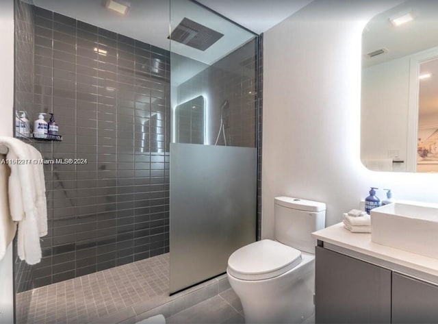 bathroom with vanity, a tile shower, tile patterned floors, and toilet