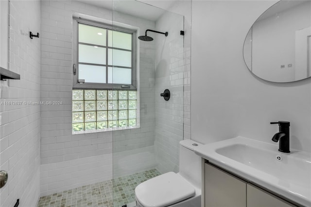 bathroom featuring vanity, toilet, a wealth of natural light, and tiled shower