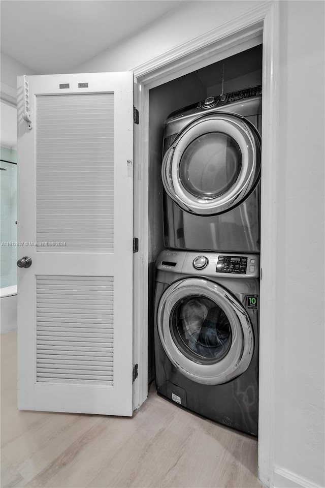 washroom featuring stacked washing maching and dryer and light hardwood / wood-style floors