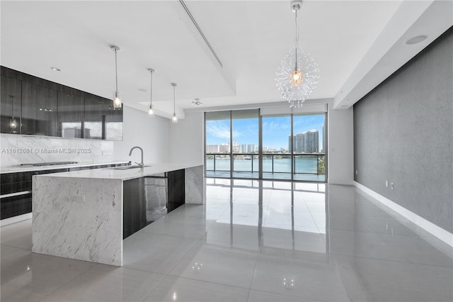 kitchen featuring a large island, hanging light fixtures, a water view, light tile patterned floors, and expansive windows