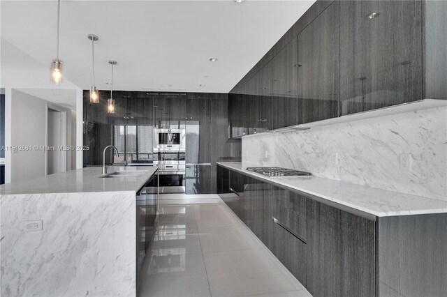 kitchen featuring decorative light fixtures, a large island, stainless steel appliances, and sink