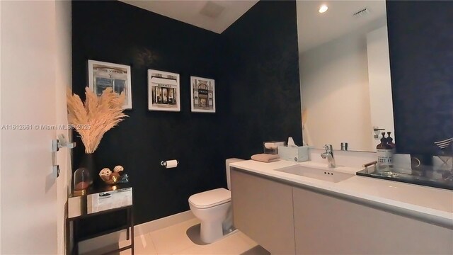 bathroom with toilet, tile patterned flooring, and sink