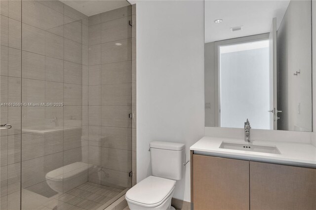 bathroom with toilet, an enclosed shower, and vanity