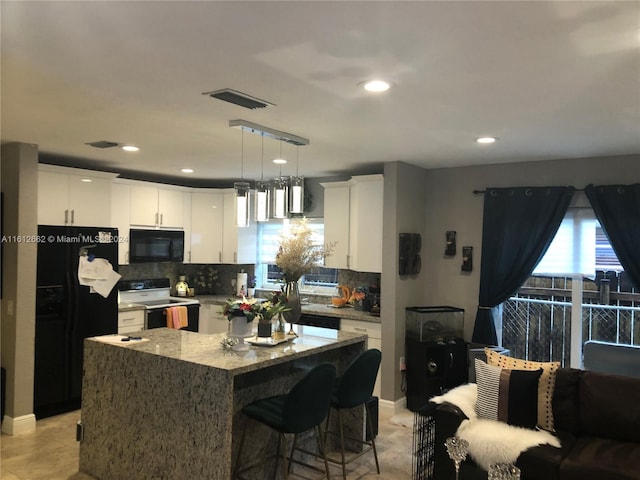 kitchen featuring black appliances, white cabinets, backsplash, and a kitchen island