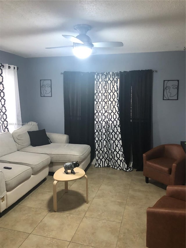 living room with light tile patterned flooring, a textured ceiling, and ceiling fan