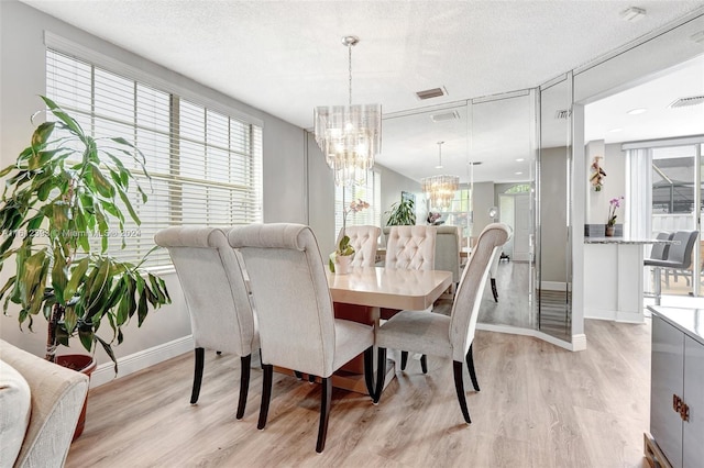 dining space featuring light hardwood / wood-style floors, a textured ceiling, a healthy amount of sunlight, and a chandelier