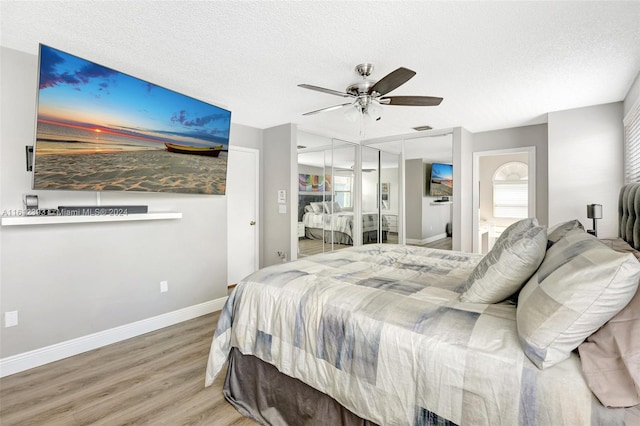 bedroom with ceiling fan, a textured ceiling, light wood-type flooring, and ensuite bathroom