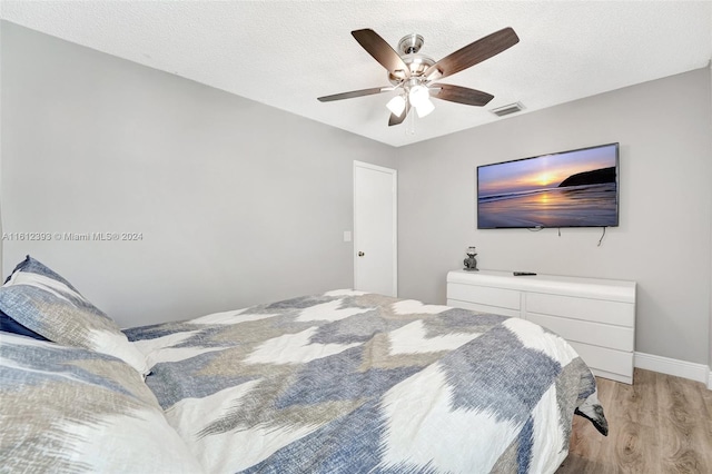 bedroom with ceiling fan, a textured ceiling, and light wood-type flooring