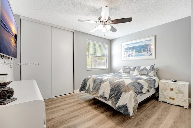 bedroom with a textured ceiling, a closet, ceiling fan, and light hardwood / wood-style flooring