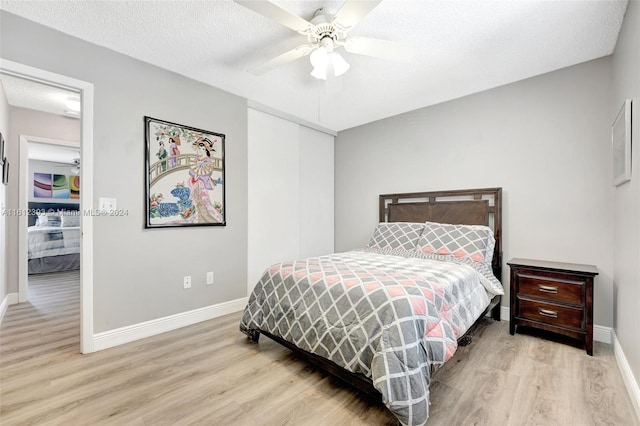 bedroom with ceiling fan, light hardwood / wood-style flooring, and a textured ceiling