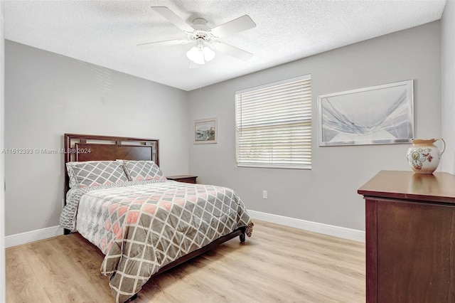 bedroom featuring ceiling fan, a textured ceiling, and light wood-type flooring