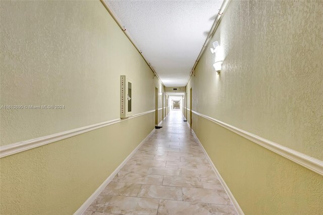 hallway featuring a textured ceiling and light tile floors