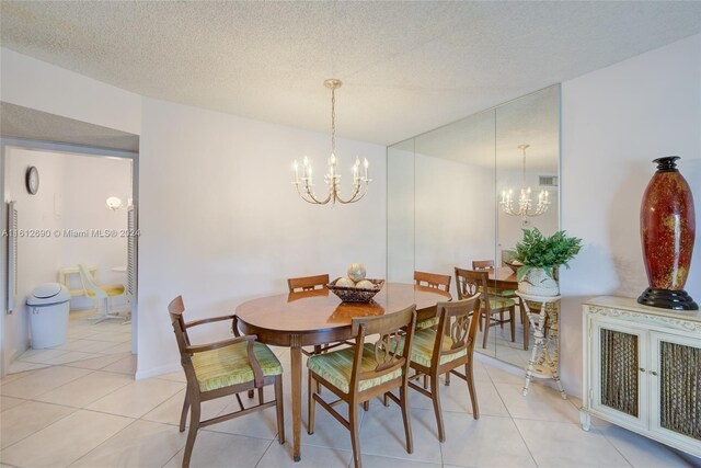 dining space with a textured ceiling, light tile floors, and an inviting chandelier