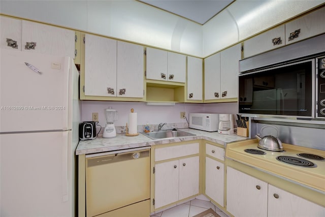 kitchen featuring white appliances, sink, and light tile floors