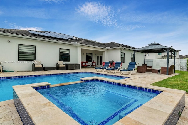 rear view of house featuring a patio, a gazebo, roof mounted solar panels, outdoor lounge area, and stucco siding