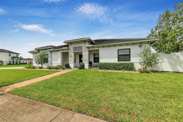 prairie-style house featuring a front lawn, fence, and stucco siding