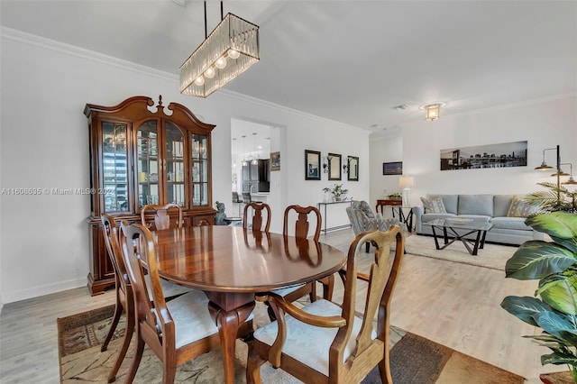 dining area with ornamental molding and light hardwood / wood-style floors