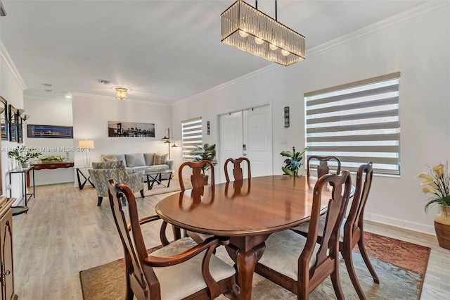 dining area with a notable chandelier, ornamental molding, and light hardwood / wood-style flooring