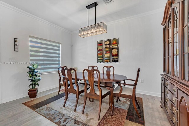 dining space featuring hardwood / wood-style floors, a chandelier, and crown molding