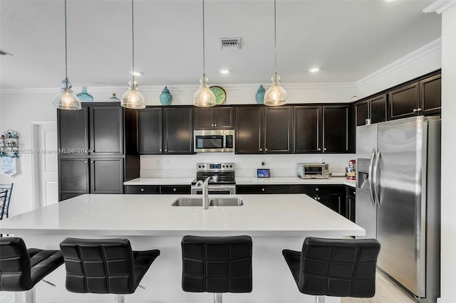 kitchen with visible vents, appliances with stainless steel finishes, a center island with sink, and decorative light fixtures