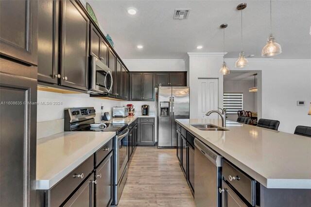 kitchen with hanging light fixtures, an island with sink, light hardwood / wood-style floors, and appliances with stainless steel finishes