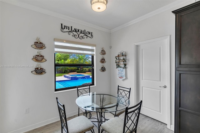 dining room featuring light wood-style floors, baseboards, and ornamental molding