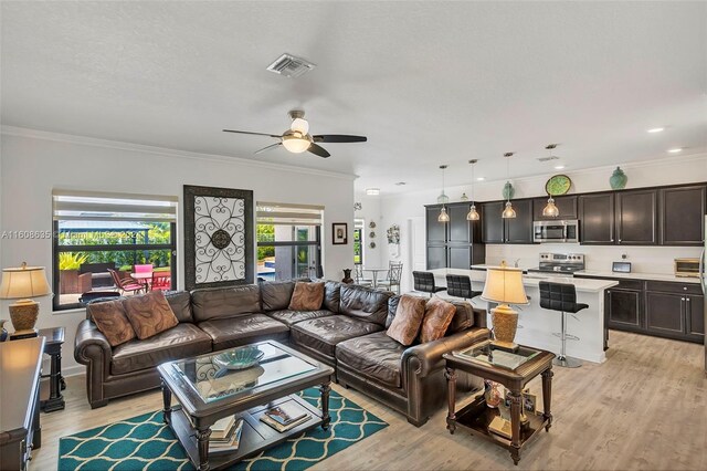 living room featuring ceiling fan, ornamental molding, and light hardwood / wood-style flooring