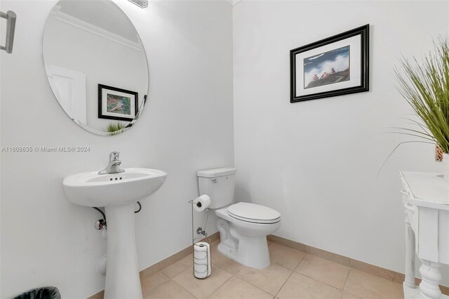 bathroom with tile flooring, toilet, and crown molding