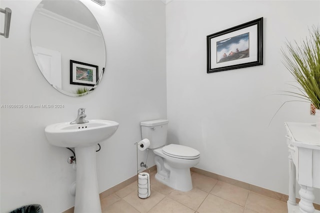 half bath with baseboards, toilet, and tile patterned floors