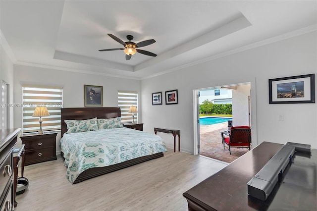 bedroom featuring ceiling fan, a tray ceiling, light wood-type flooring, access to outside, and ornamental molding