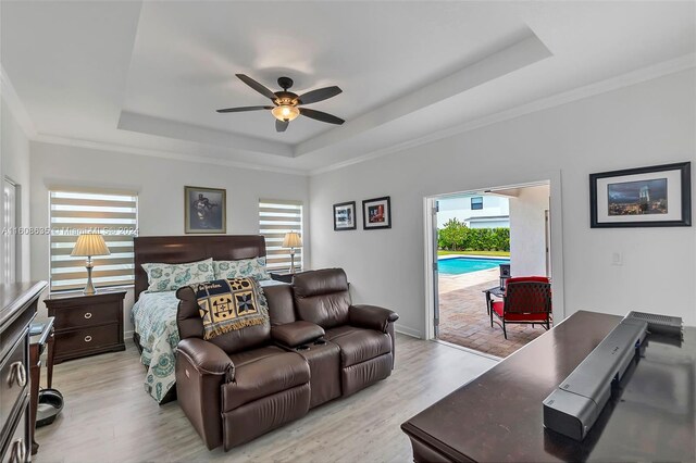 bedroom featuring a raised ceiling, light hardwood / wood-style flooring, and access to exterior