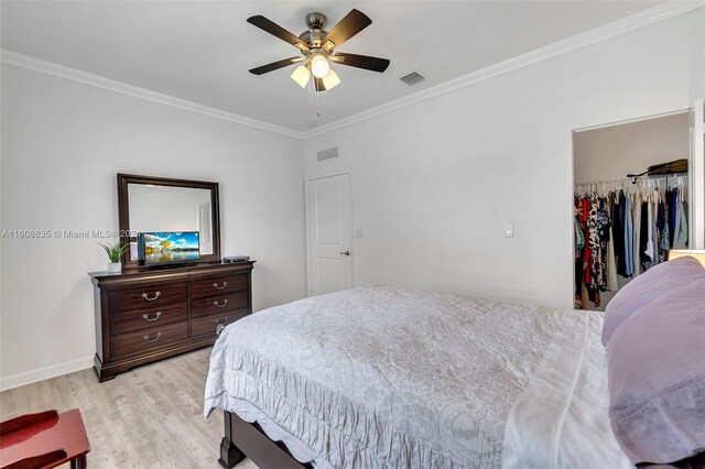 bedroom featuring ceiling fan, a closet, light hardwood / wood-style floors, crown molding, and a walk in closet