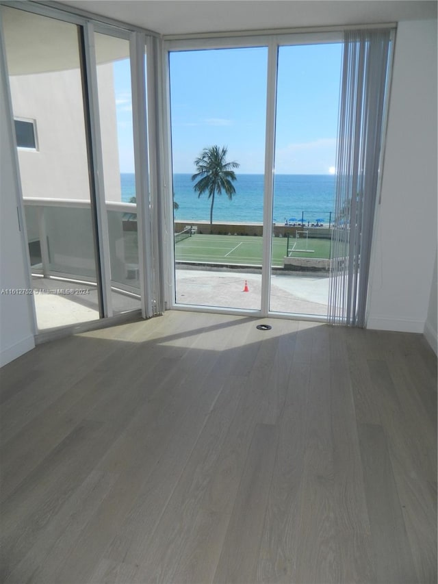 unfurnished room with a water view, a wall of windows, and hardwood / wood-style flooring