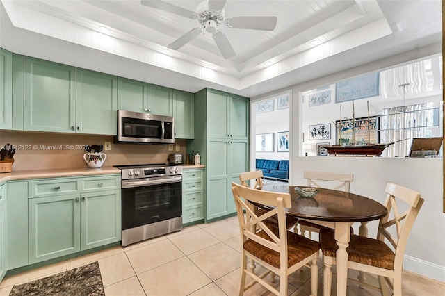 kitchen featuring a raised ceiling, green cabinets, light tile patterned floors, and stainless steel appliances