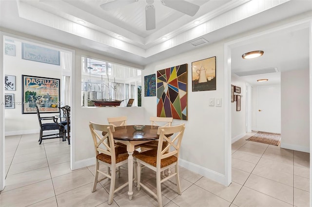 tiled dining room featuring a tray ceiling and ceiling fan