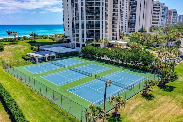 view of tennis court with a water view and a lawn