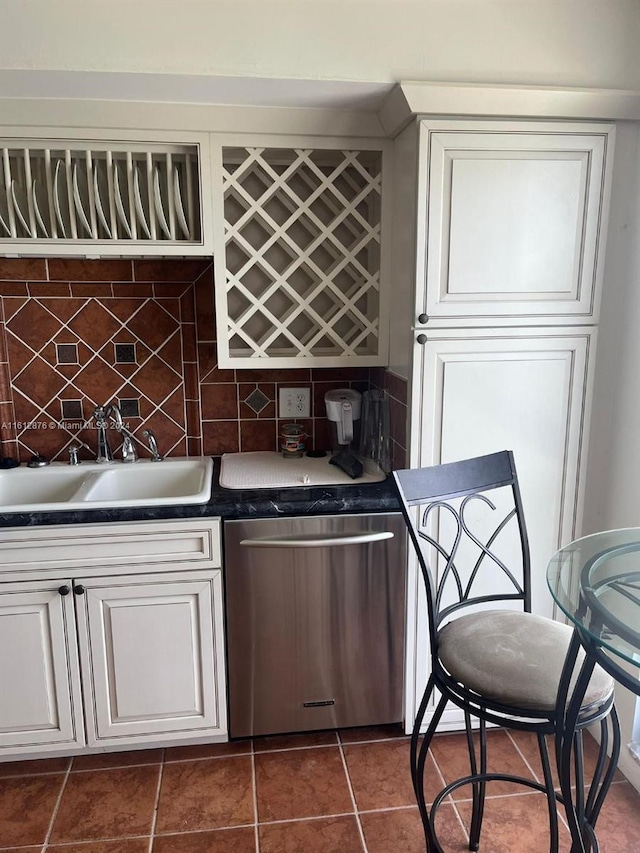 kitchen with dark tile patterned flooring, sink, and stainless steel dishwasher