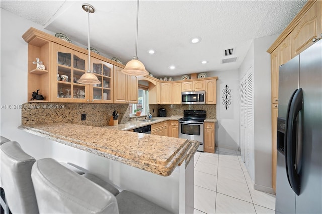 kitchen featuring backsplash, light tile patterned floors, decorative light fixtures, kitchen peninsula, and stainless steel appliances