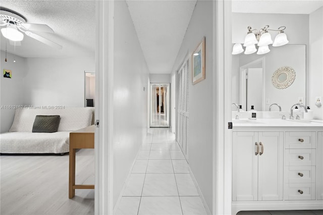 corridor with a textured ceiling, light tile patterned floors, and sink