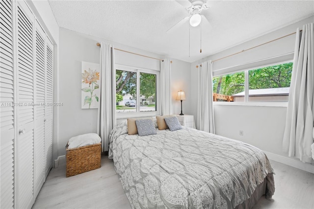 bedroom featuring multiple windows, ceiling fan, a closet, and a textured ceiling