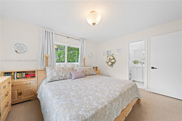 carpeted bedroom featuring a textured ceiling and ensuite bathroom