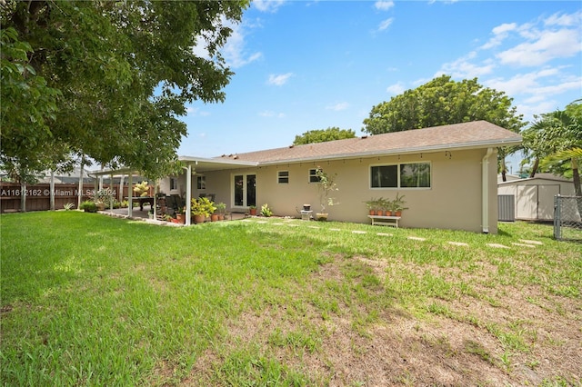 back of property with a yard, a patio, and a shed