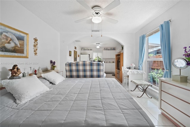 tiled bedroom with a textured ceiling, white refrigerator, and ceiling fan