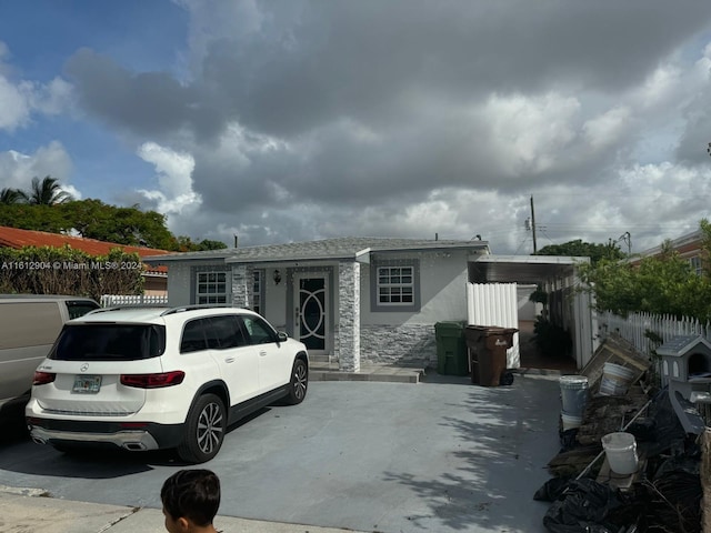 view of front of house with stone siding, fence, and stucco siding