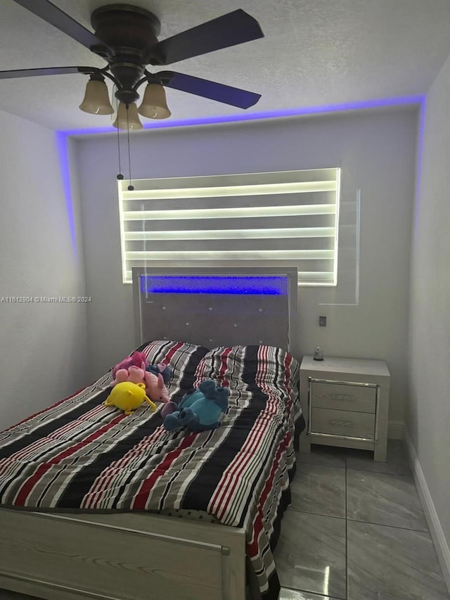 bedroom with a ceiling fan, multiple windows, a textured ceiling, and baseboards