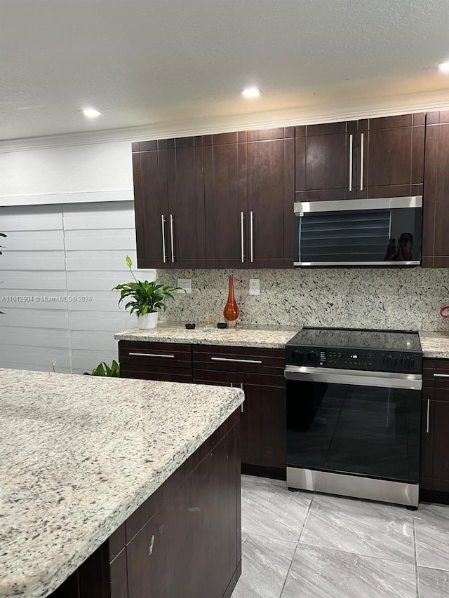 kitchen featuring light stone countertops, dark brown cabinetry, range with electric cooktop, and backsplash